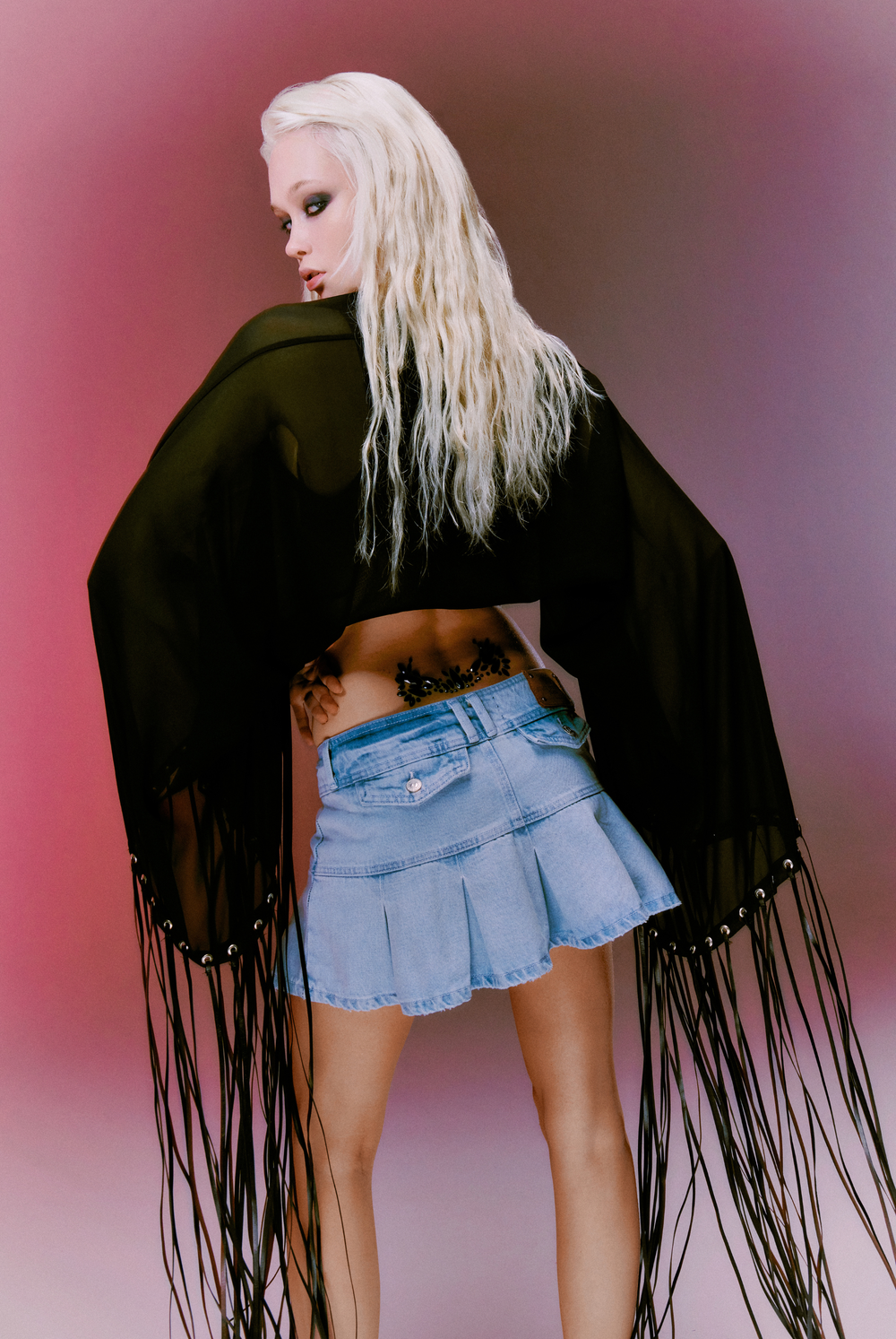 Displays a model wearing the light wash  'juicy' branded denim pleated mini skirt 