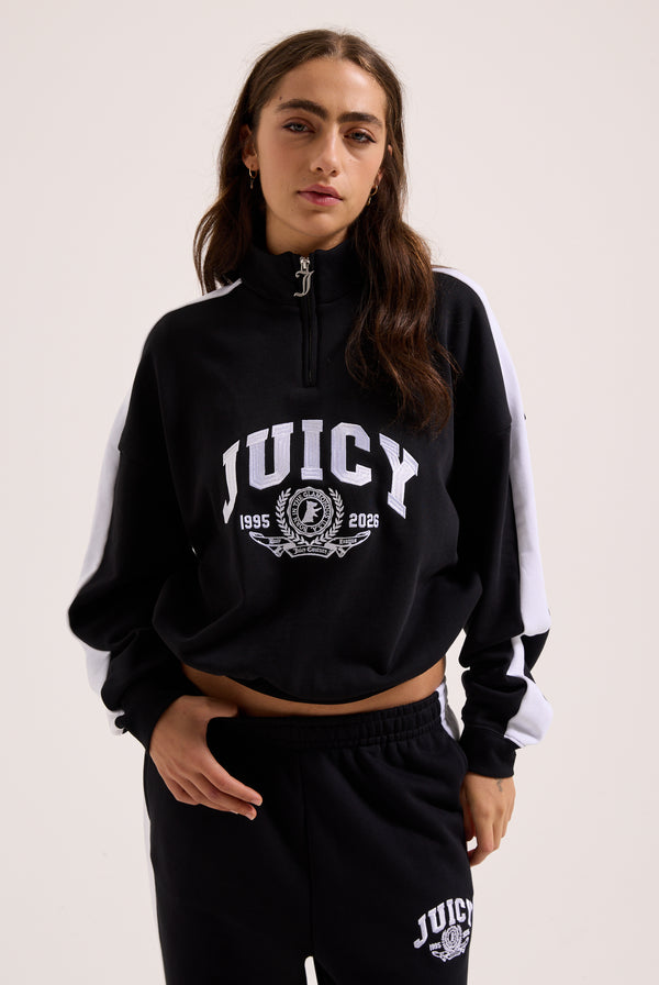 Displays a model wearing the Black 'Juicy' branded college crest track top 