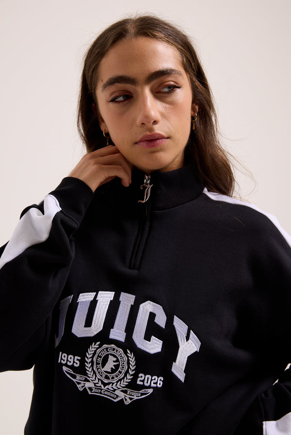 Displays a model wearing the Black 'Juicy' branded college crest track top 