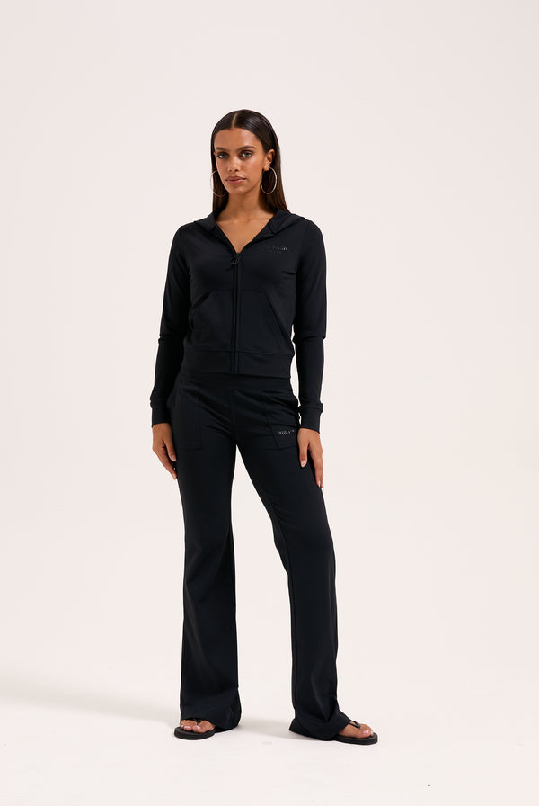 Displays a model wearing the black 'juicy' branded peached active low rise pants 