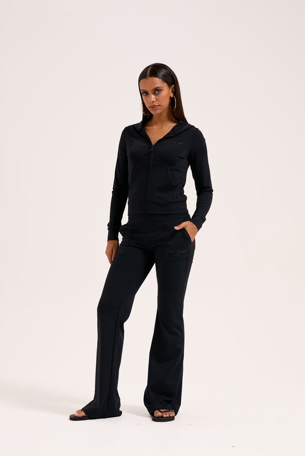 Displays a model wearing the black 'juicy' branded peached active low rise pants 