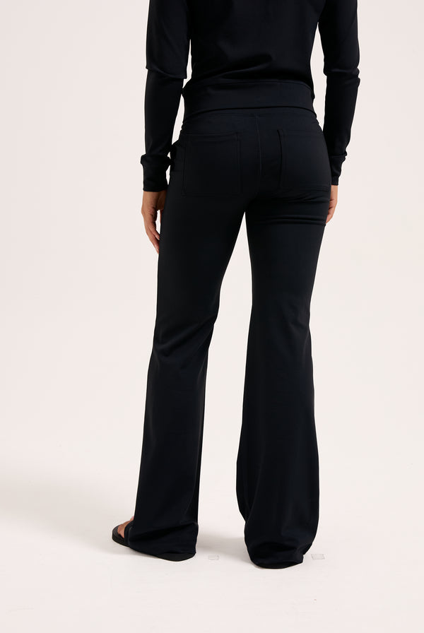 Displays a model wearing the black 'juicy' branded peached active low rise pants 