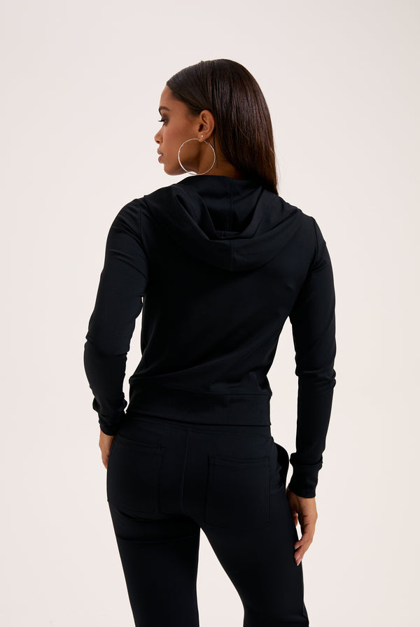 Displays a model wearing the black 'juicy' branded peached active low rise pants 