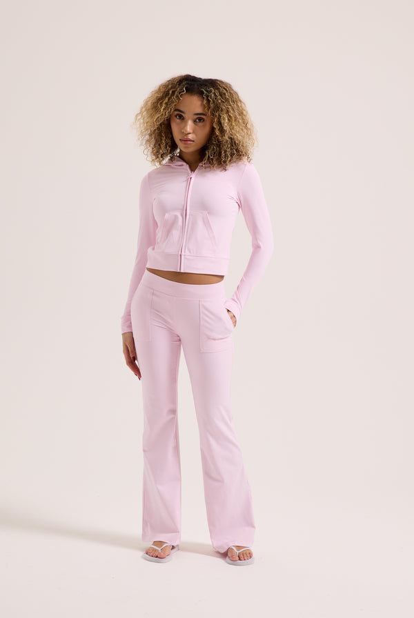 Displays a model wearing the Cherry Blossom 'Juicy' branded peached active low rise pants 