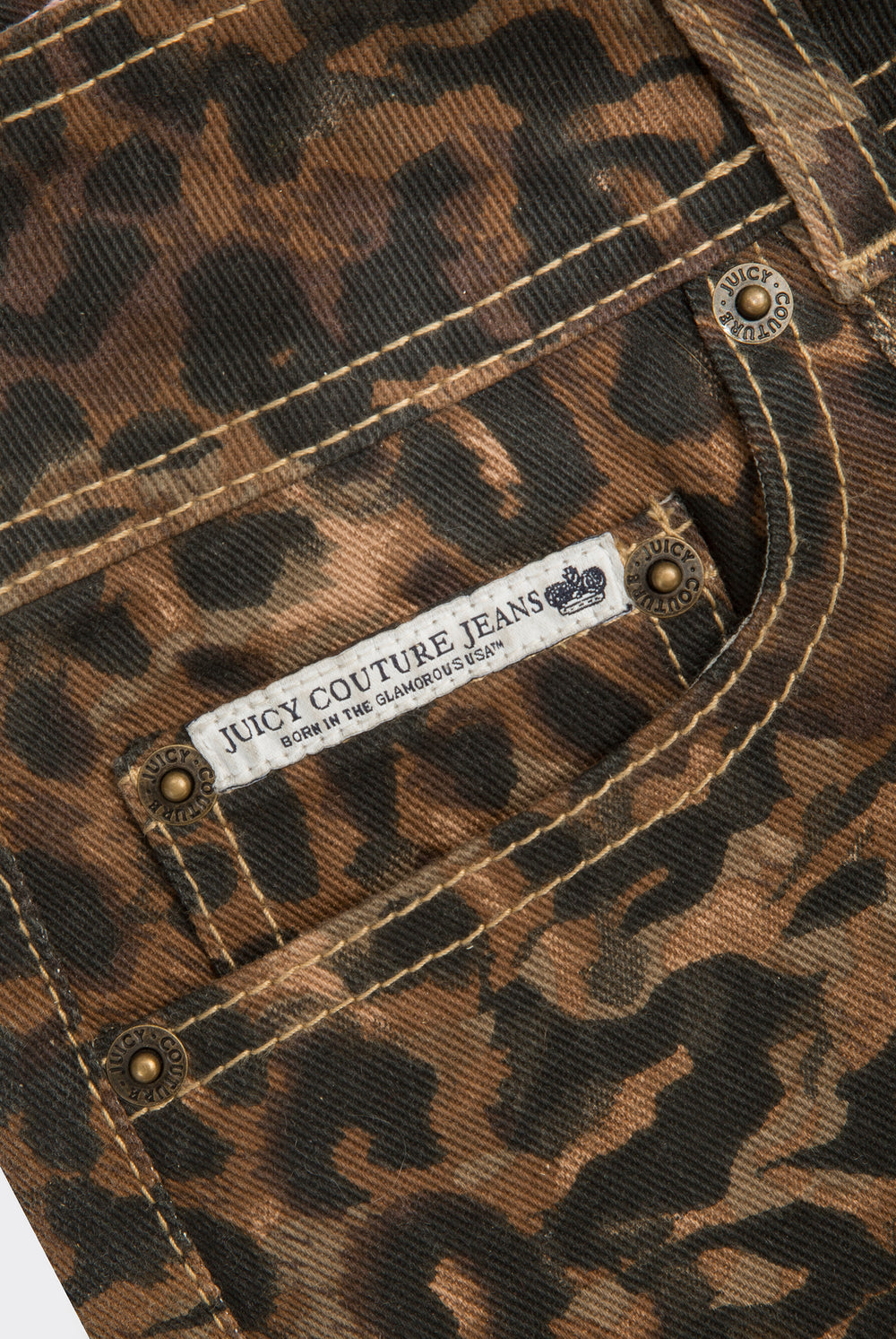 Displays the animal 'Juicy' branded denim lace up shorts featuring the close up on the juicy couture jeans 