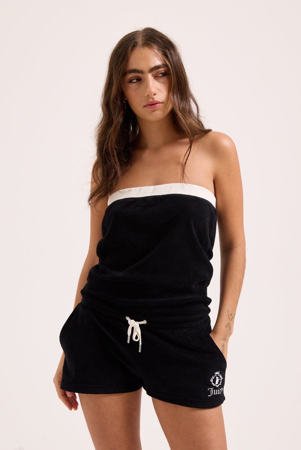 Displays a model wearing the Black Appliqué 'Juicy' branded Terry towelling romper 