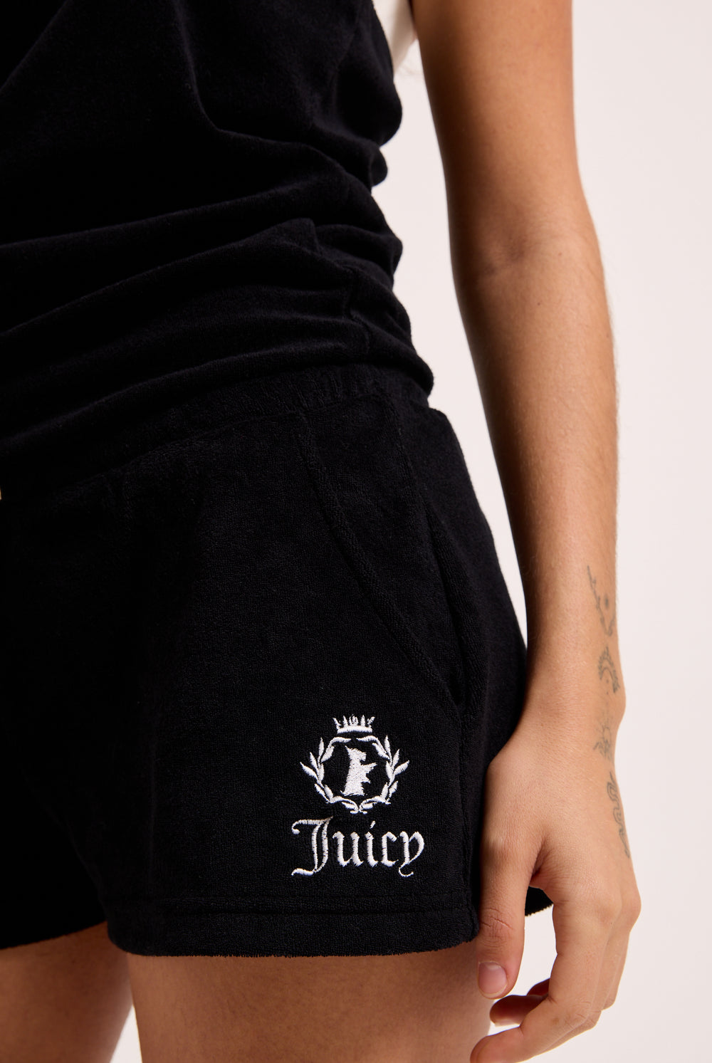 Displays a model wearing the Black Appliqué 'Juicy' branded Terry towelling romper featuring the juicy logo