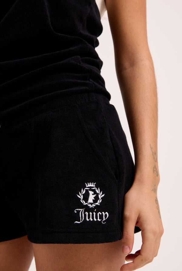 Displays a model wearing the Black Appliqué 'Juicy' branded Terry towelling romper featuring the juicy logo
