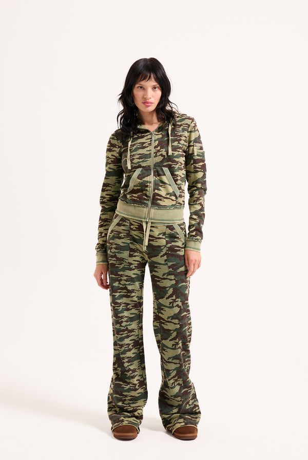 Displays a model wearing the Camo Print 'Juicy' branded washed cotton low rise track bottoms