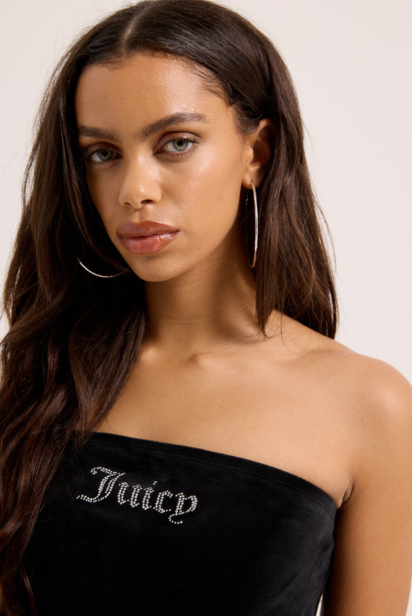 Displays a model wearing the Black Bandeau Ruffle 'Juicy' branded velour dress 