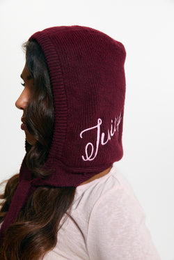 Displays a model wearing the Burgundy 'Juicy' branded Bonnet With Bow