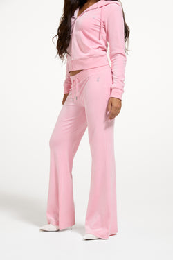Displays a model wearing the Juicy Pink 'Juicy' branded bridesmaid classic velour low rise track pants 