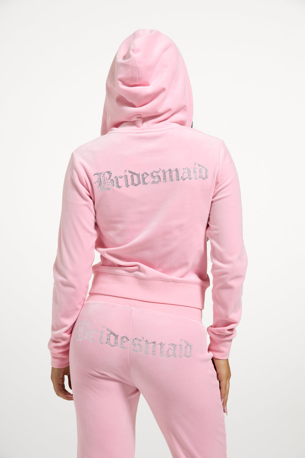 Displays a model wearing the Juicy Pink 'Juicy' branded bridesmaid classic velour low rise track pants 
