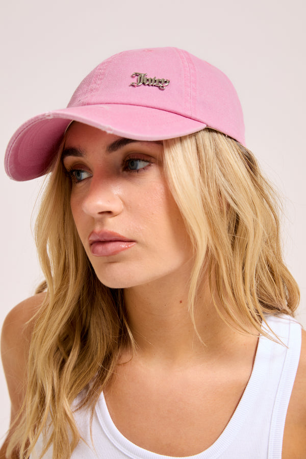Displays a model wearing the pink 'juicy' branded distressed cotton denim cap 