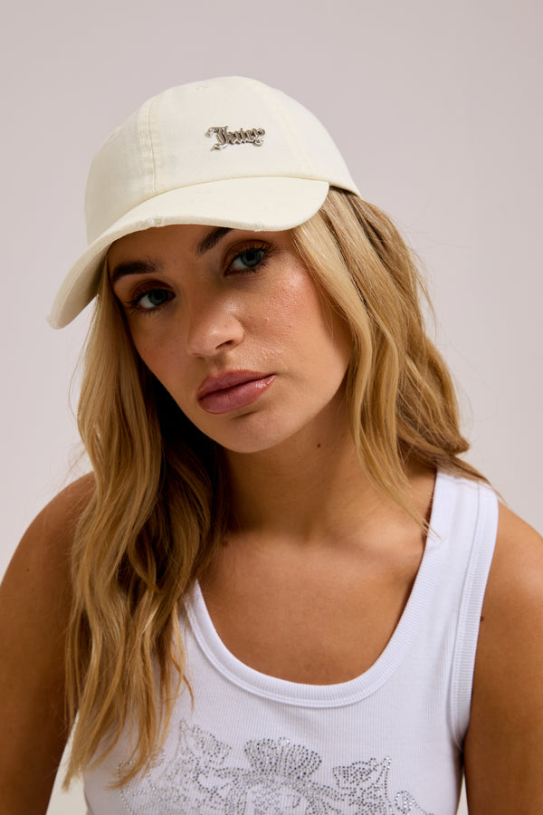 Displays a model wearing the Ecru distressed 'Juicy' branded cotton denim cap 