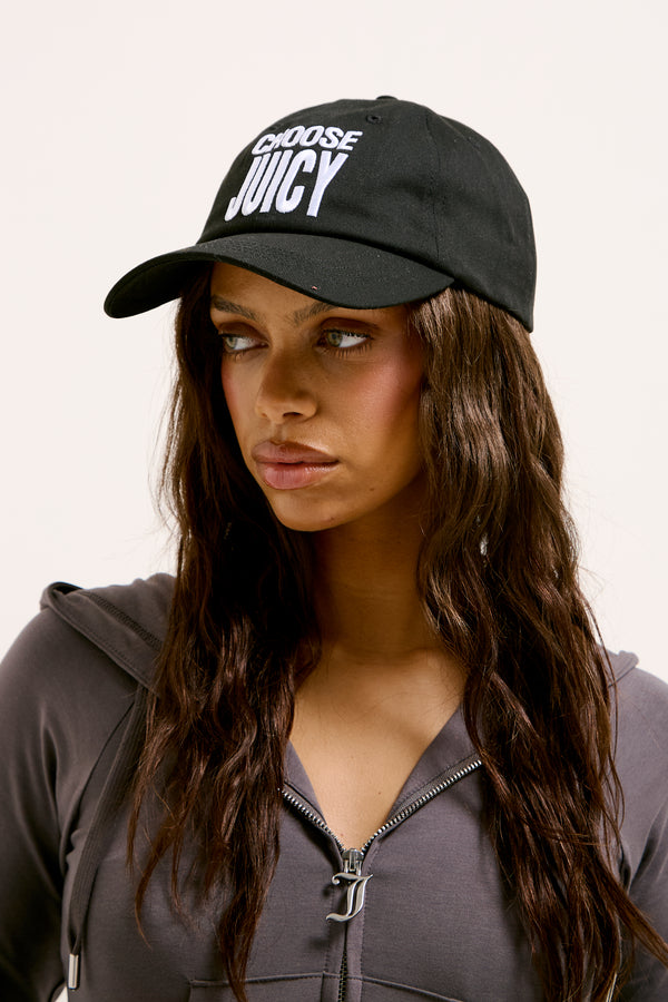 Displays a model wearing the Black 'Juicy' branded Choose Juicy cap 