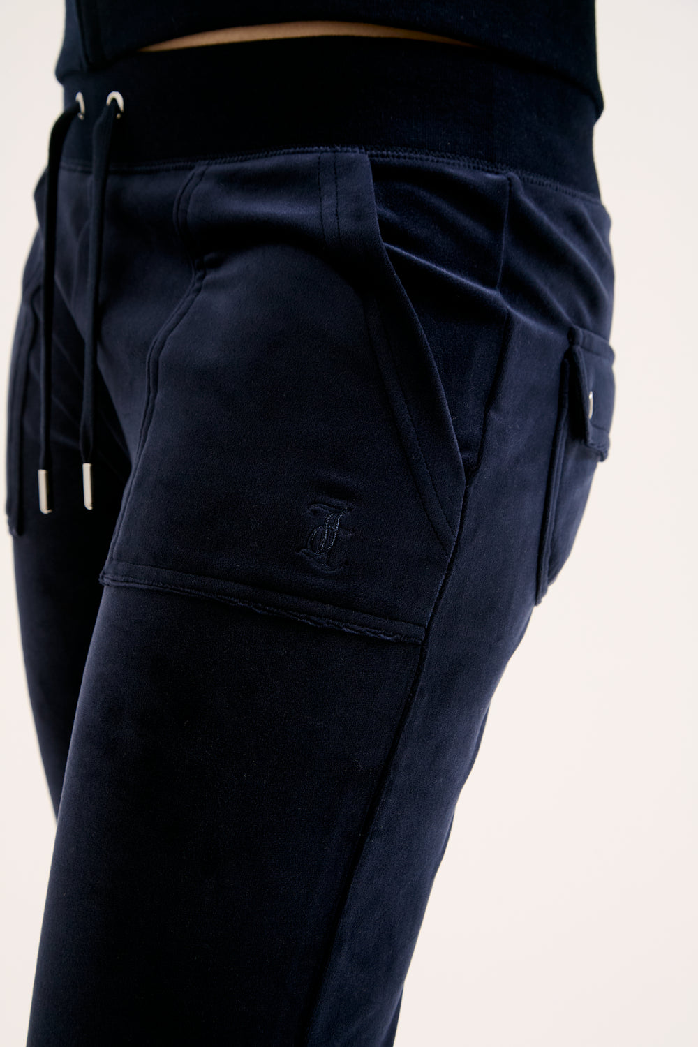 Navy pants with drawstring waistband and multiple pockets on a light pink background