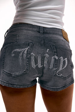 Displays a model wearing the Washed Black 'Juicy' branded low rise denim booty shorts 