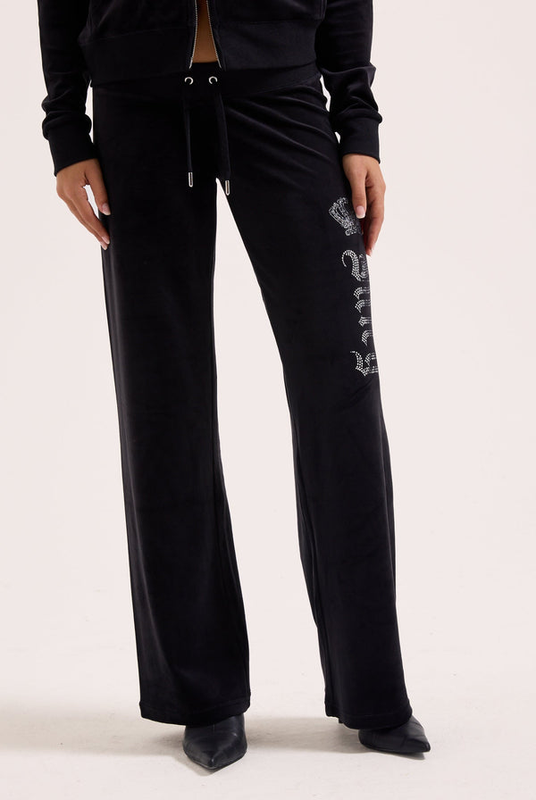 Displays a model wearing the black 'juicy' branded diamanté crown OG Straight low rise velour bottoms 