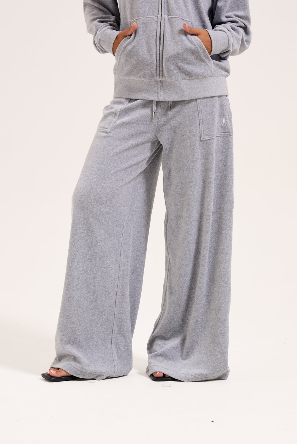Displays a model wearing the silver marl wide leg 'Juicy' branded cotton velour track pant