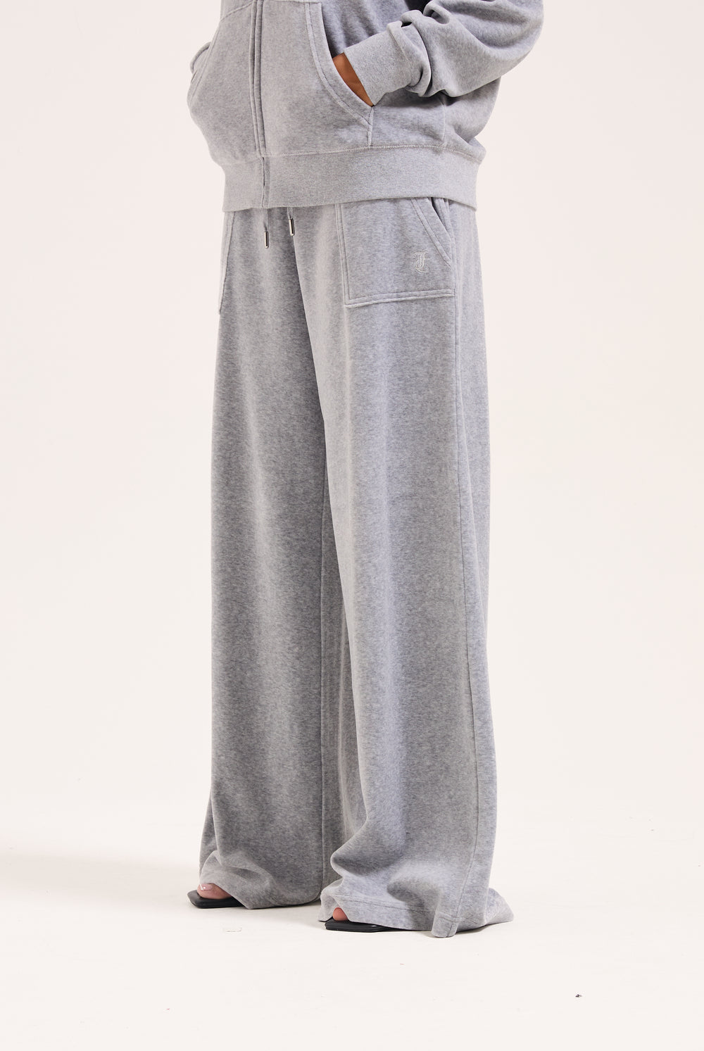 Displays a model wearing the silver marl wide leg 'Juicy' branded cotton velour track pant