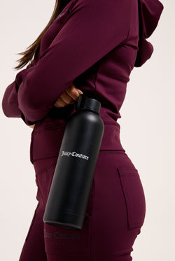 Displays a model holding the Black 'Juicy' heritage crest water bottle 
