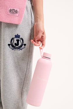 Displays a model holding the Pink 'Juicy' branded heritage crest water bottle 