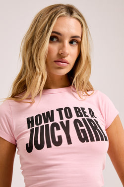 Displays a model wearing the Juicy Pink 'Juicy' branded HOW TO BE A JUICY GIRL T-Shirt