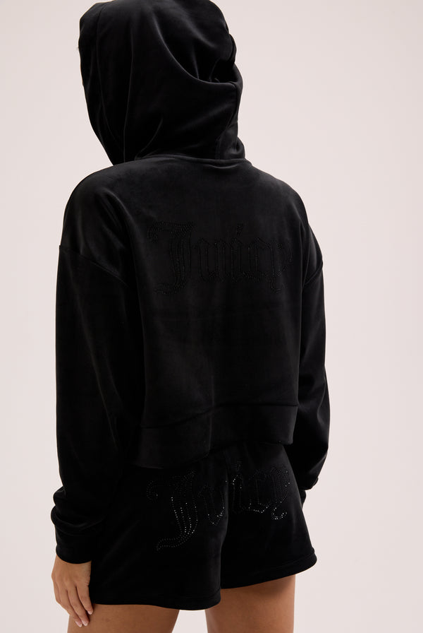 Displays a model wearing the Black 'Juicy' branded velour outline diamanté track shorts 
