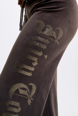 Displays a model wearing the Java 'Juicy' branded Old Gothic Diamante Og Straight Leg Trackpant featuring close up on the juicy branding 