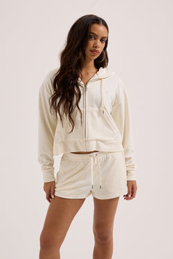 Displays a model wearing the Cream Outline 'Juicy' branded diamanté oversized cropped hoodie