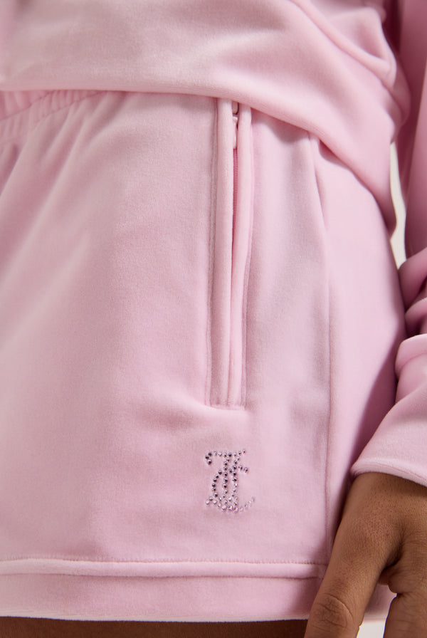 Displays a model wearing the Cherry Blossom 'Juicy' branded velour outline diamanté track shorts featuring the juicy Couture logo
