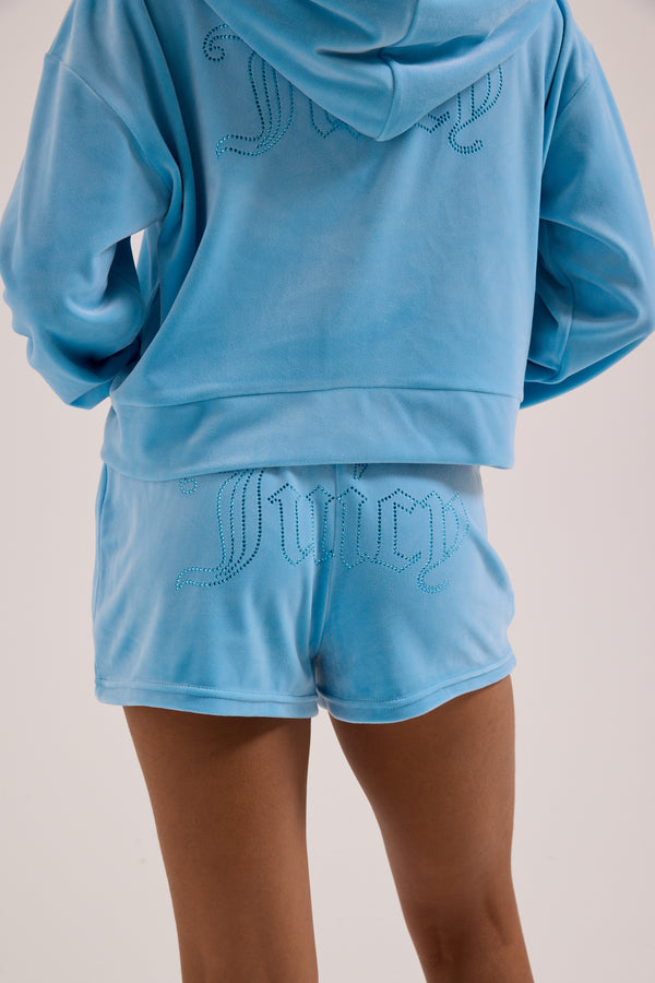 Displays a model wearing the Sky Blue 'juicy' branded Velour outline diamanté track shorts 
