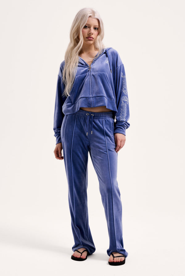 Displays a model wearing the grey blue 'Juicy' branded velour outline diamanté tracksuit bottom