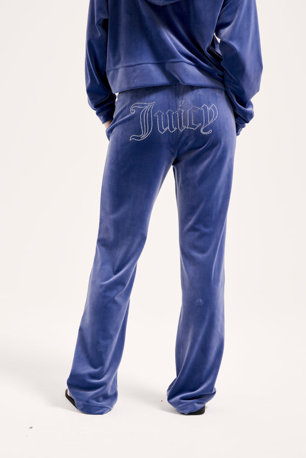 Displays a model wearing the grey blue 'Juicy' branded velour outline diamanté tracksuit bottom