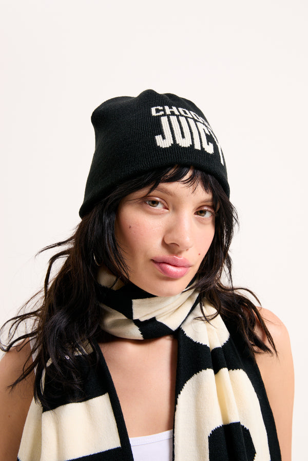 Displays a model wearing the 'Choose Juicy' knitted scarf and beanie 
