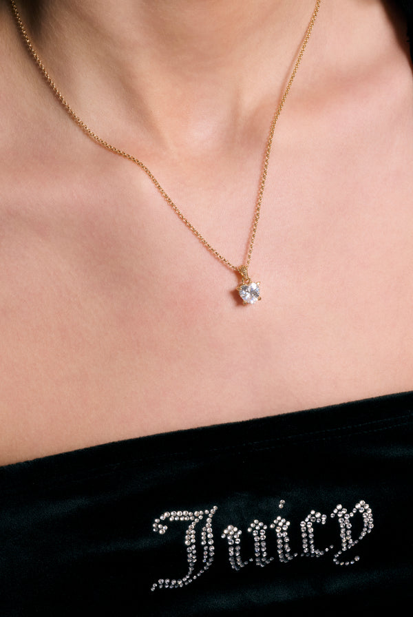 Displays a model wearing the Gold Tone 'Juicy' branded solitaire crystal heart pendant 