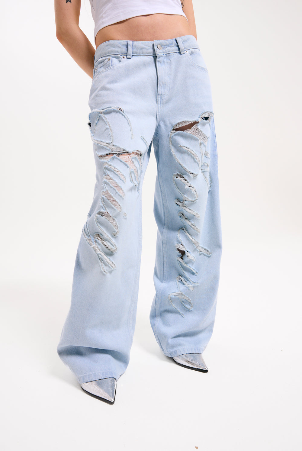 Displays a model wearing the Bleached 'Juicy' branded denim distressed wide leg jeans 