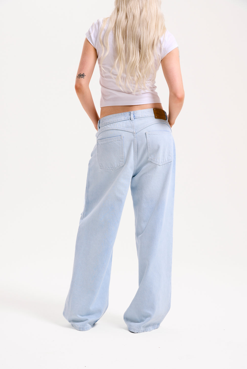Displays a model wearing the Bleached 'Juicy' branded denim distressed wide leg jeans 