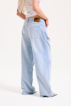 Displays a model wearing the Bleached 'Juicy' branded denim distressed wide leg jeans 