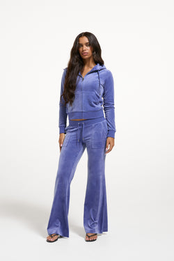 Displays a model wearing the Grey&blue 'Juicy' branded Low Rise Flare Classic Velour Track Pant