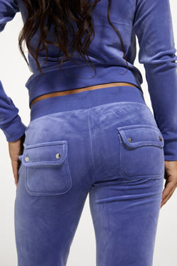 Displays a model wearing the Grey&blue 'Juicy' branded Low Rise Flare Classic Velour Track Pant