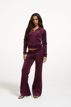 Displays a model wearing the Winetasting & Gold 'Juicy' branded Low Rise Flare Classic Velour Track Pant