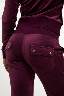 Displays a model wearing the Winetasting & Gold 'Juicy' branded Low Rise Flare Classic Velour Track Pant
