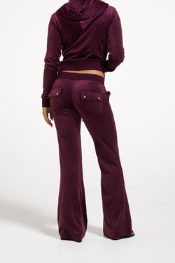 Displays a model wearing the Winetasting & Gold 'Juicy' branded Low Rise Flare Classic Velour Track Pant