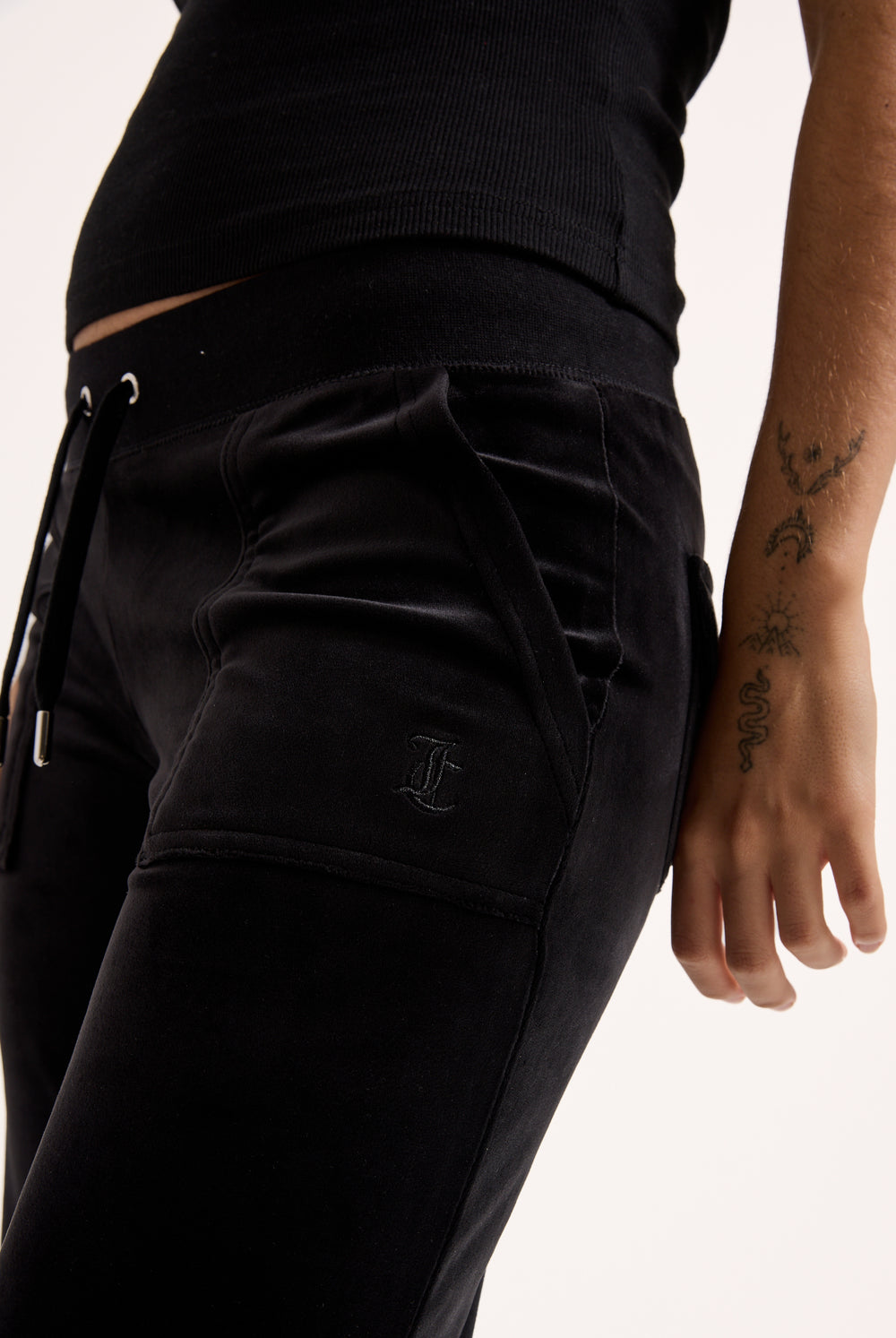 Displays a model wearing the Black Low rise flare pocket 'Juicy' branded classic velour track pant