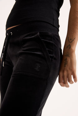 Displays a model wearing the Black Low rise flare pocket 'Juicy' branded classic velour track pant