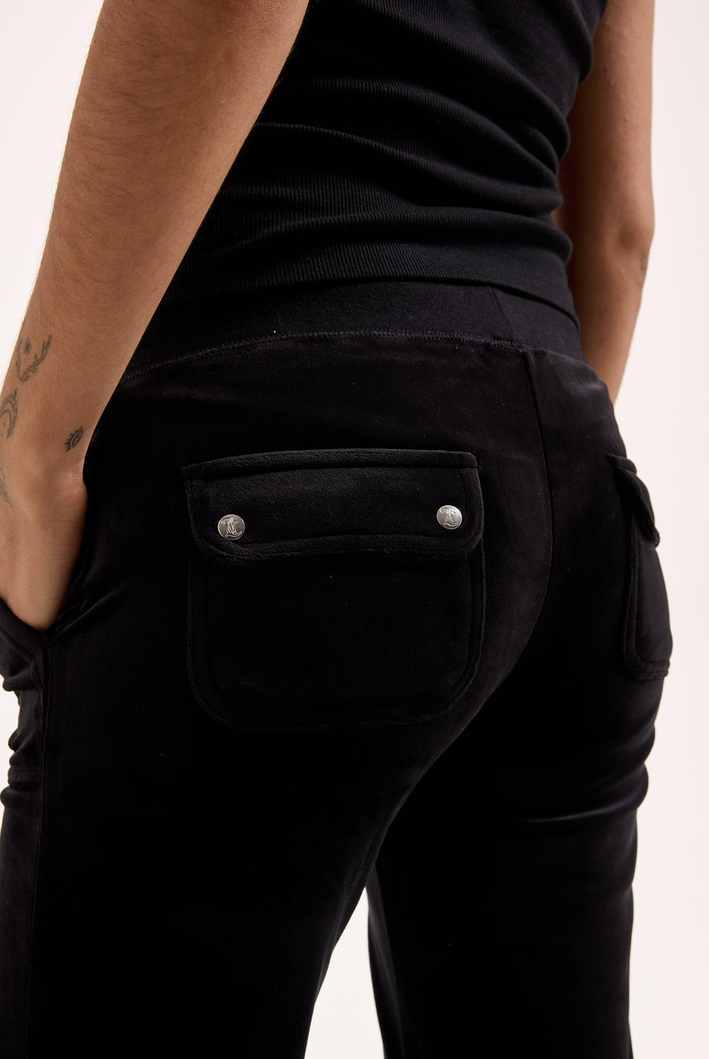 Displays a model wearing the Black Low rise flare pocket 'Juicy' branded classic velour track pant