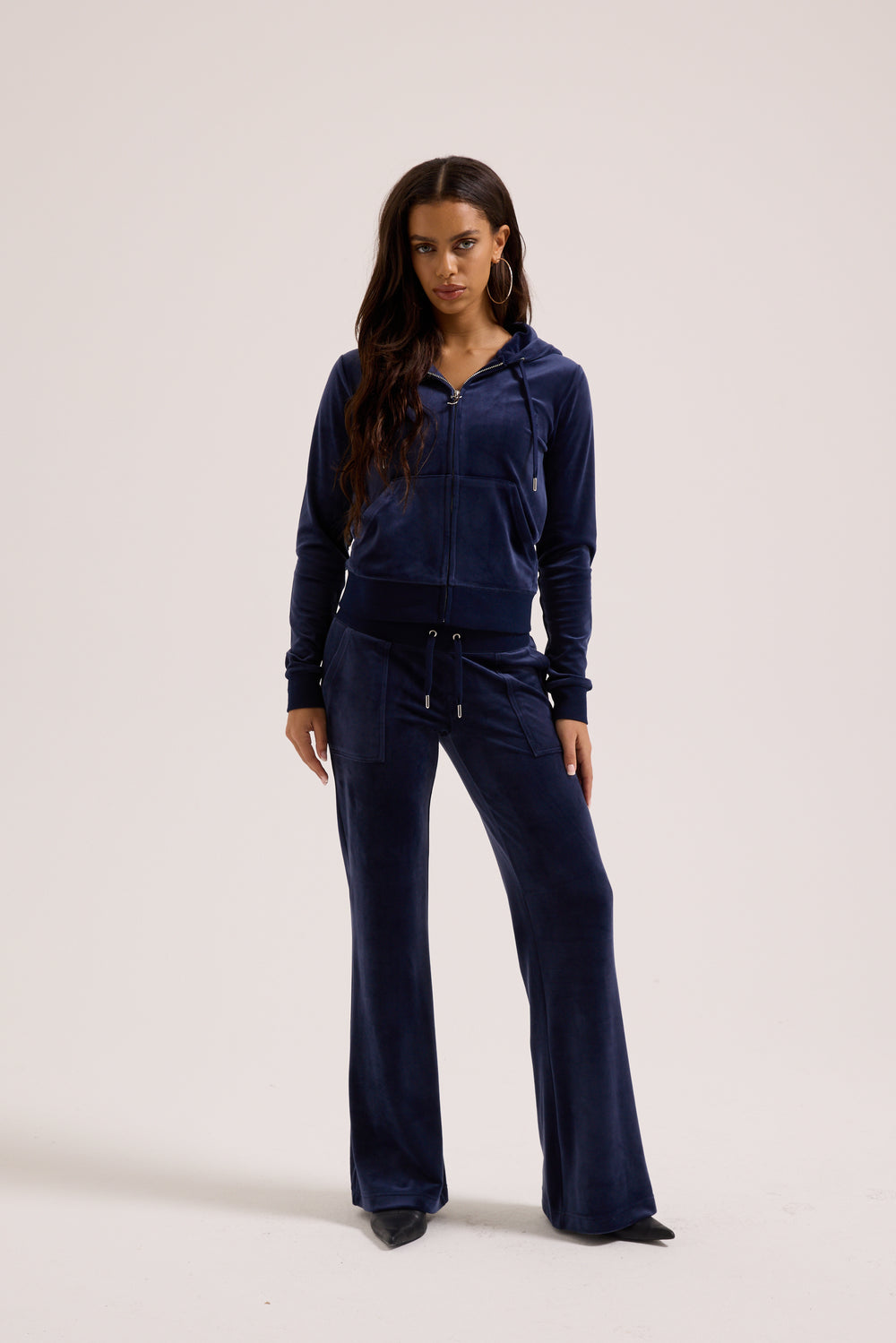 Displays a model wearing the Night Sky 'Juicy' branded low rise velour track pants 