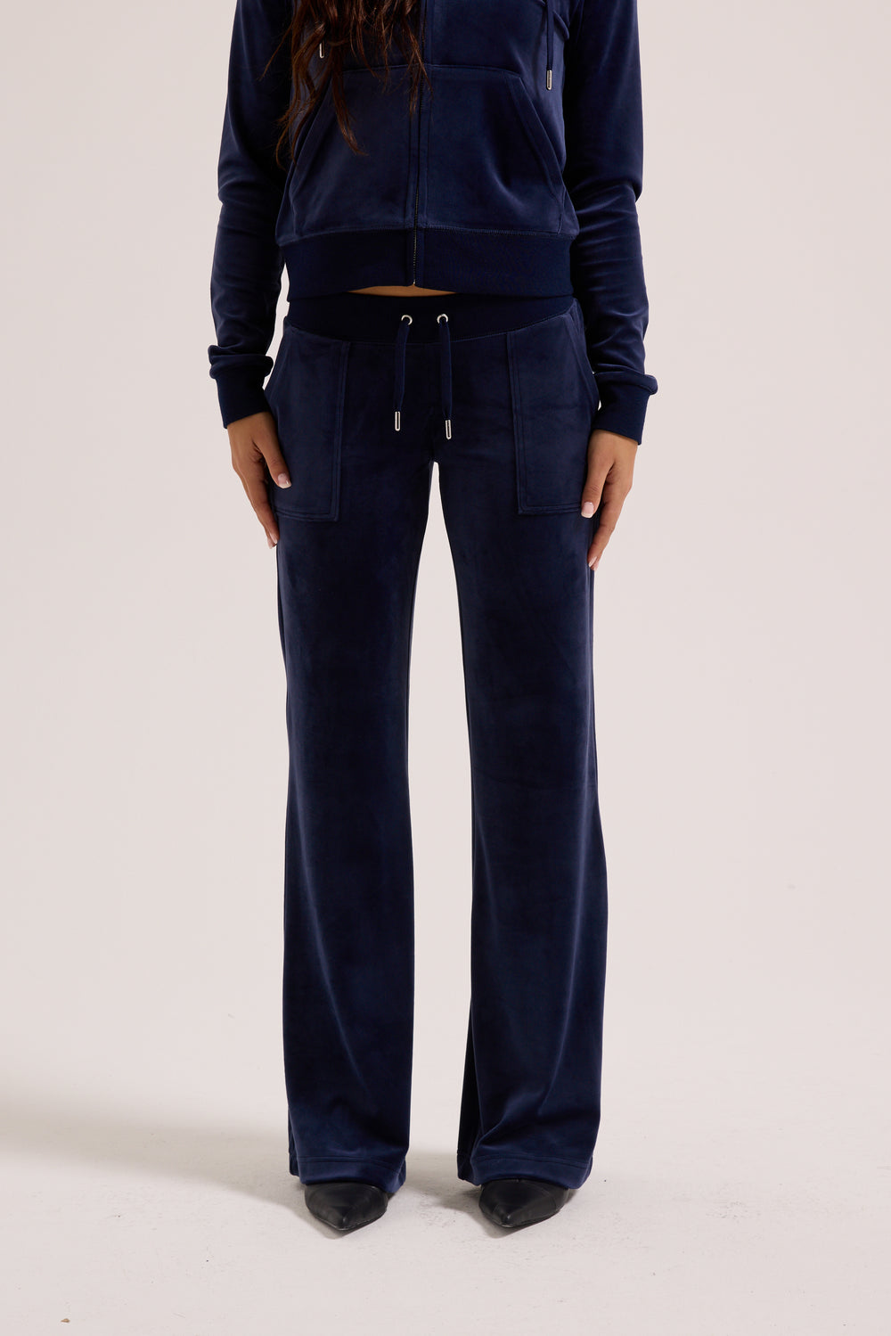 Displays a model wearing the Night Sky 'Juicy' branded low rise velour track pants 
